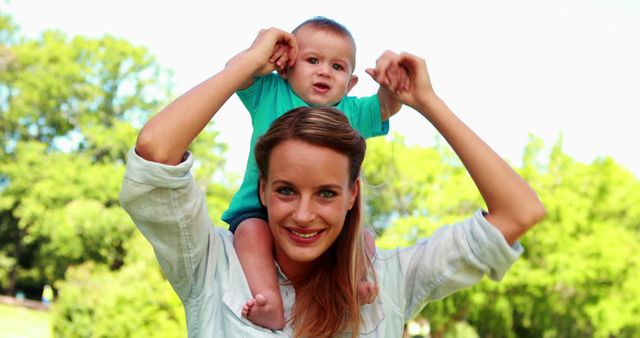 Smiling Mother Holding Baby on Shoulders in Park - Download Free Stock Images Pikwizard.com