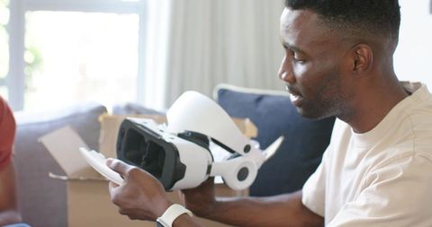 Man Unboxing VR Headset on Sofa in Bright Living Room Testing New Virtual Reality Gadget
