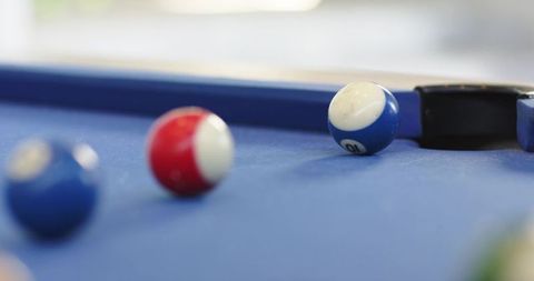 Blue-and-white 10 ball sitting beside corner pocket on blue pool table felt