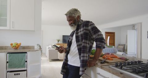 Senior man using smartphone in modern kitchen