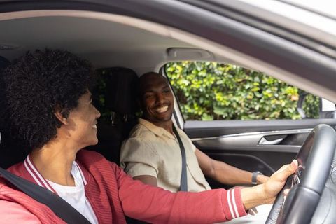 Young african american driver smiling with older african american passenger during car ride
