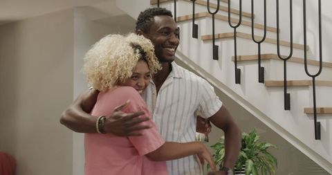 Couple Embracing at Home by Modern Staircase