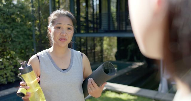 Woman Preparing for Outdoor Yoga Session with Water Bottle and Mat - Download Free Stock Images Pikwizard.com