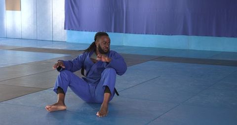 Martial artist practicing techniques on blue gym mat