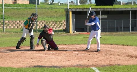 Adult baseball game with batter swinging, umpire and catcher ready
