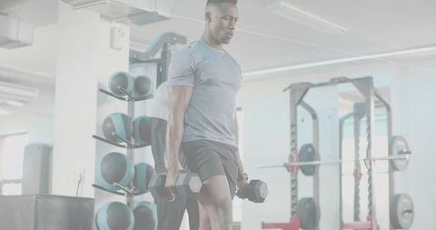 Athletic man holding hex dumbbells performing weighted lunge in bright commercial gym