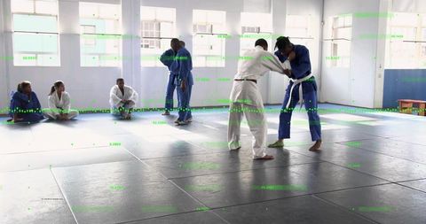 Grappling training in bright dojo with judo gis, white belts, mats and focused athletes