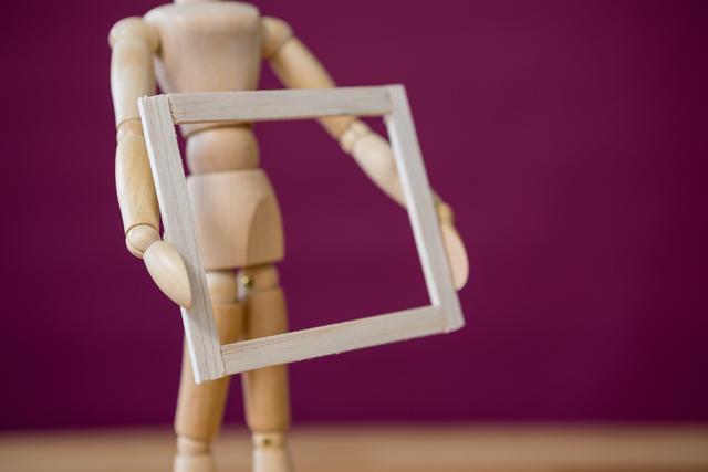 Conceptual image of figurine holding wooden picture frame