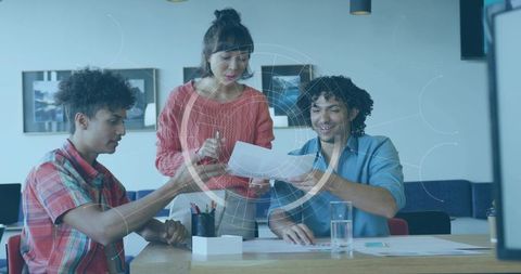 Female Team Lead Reviewing Documents with Colleagues at Coworking Table, Brainstorming