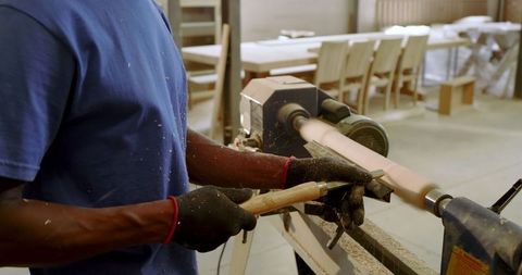 Craftsman shaping wood on lathe in busy workshop