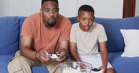 Father and Son Gaming on Couch with Popcorn