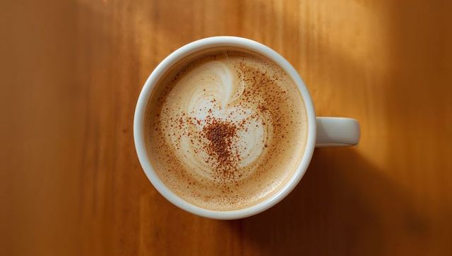 Top-Down Latte Art Heart with Cocoa Dust in White Mug on Warm Wooden Table