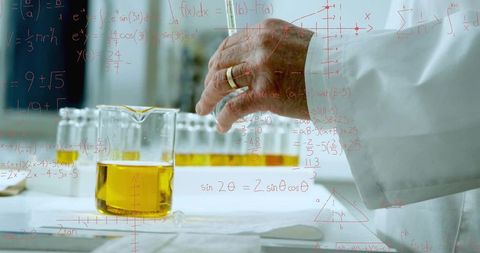 Senior chemist pouring amber solution in beaker on laboratory bench with test vials