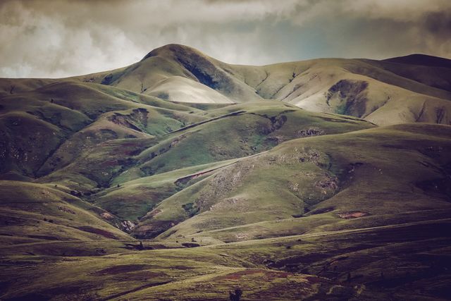 Captures rolling green hills under a cloudy sky, providing a serene and peaceful countryside view. Ideal for use in nature-themed blogs, relaxation content, travel advertisements, scenic calendars, and environmental campaigns.