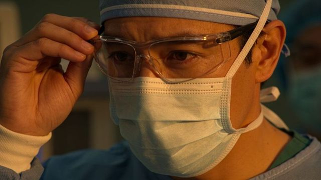 Surgeon adjusting protective goggles in operating room close-up, focused healthcare worker