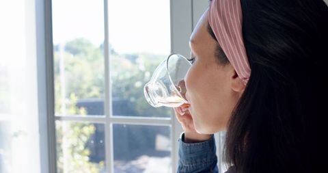 Woman relaxing by window sipping drink and enjoying nature