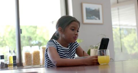 Young Girl Using Smartphone at Home in Casual Kitchen Setting
