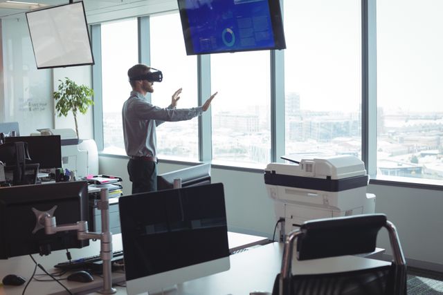 Businessman using virtual reality technology in a modern office with large windows and city view. Ideal for illustrating concepts of innovation, technology in business, and modern work environments. Suitable for use in articles, presentations, and marketing materials related to corporate technology, VR applications, and futuristic workplaces.