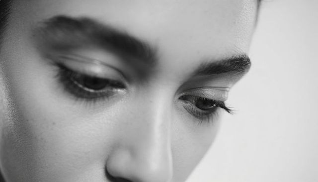 Monochrome closeup woman looking down emphasizing eyelashes, brows, skin texture