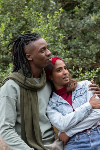 Young couple embracing on park rock with olive scarf and red headband