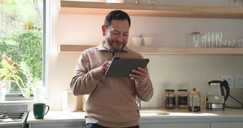 Mature Asian Man Enjoying Tablet Time in Contemporary Kitchen