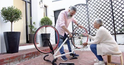 Senior Couple Fixing Bicycle Together Outdoors