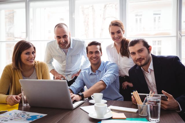 Group of business professionals collaborating around a laptop in a modern office. Ideal for illustrating teamwork, corporate meetings, business strategy sessions, and creative office environments. Perfect for business presentations, websites, and marketing materials.