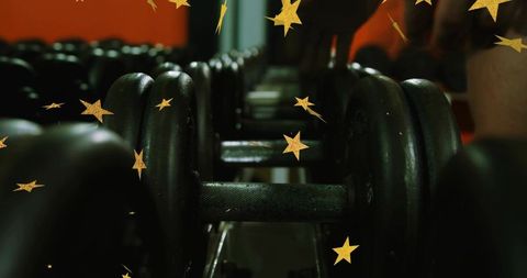 Row of dumbbells gliding into blur on metal rack, gold star overlay, gym fitness concept