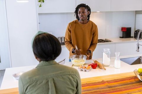 Couple mixing batter at bright modern kitchen island whisking ingredients together