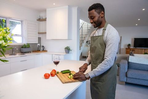 Man Cooking at Home Slicing Vegetables with Wine Glass Nearby