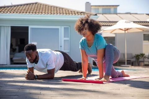 Diverse couple exercising together by a sunny poolside