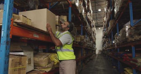 Warehouse Worker Organizing Boxes on Shelves in Aisle