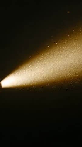 Starting Spotlight Projecting Golden Beam Revealing Dust Motes in Dark Studio Vertical Video