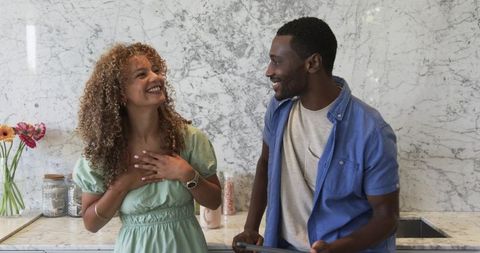 Smiling couple sharing joyful moment in modern marble kitchen with tablet