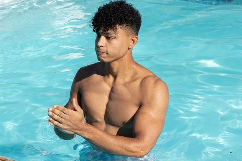 African american athletic man standing in pool clasping hands sunlit water reflections