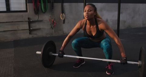 Determined female athlete performing barbell squats at gym