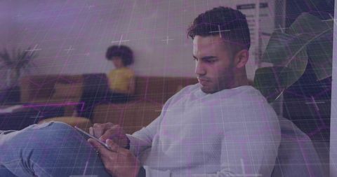 Man using tablet on couch with purple augmented reality grid for tech app concept