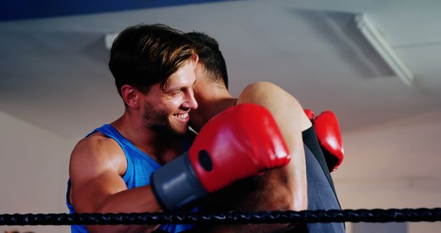 Two young Caucasian men are engaged in a friendly embrace in a boxing ring, with one wearing boxing gloves. Their sportsmanship showcases the respect and camaraderie that can exist between competitors in athletic environments.