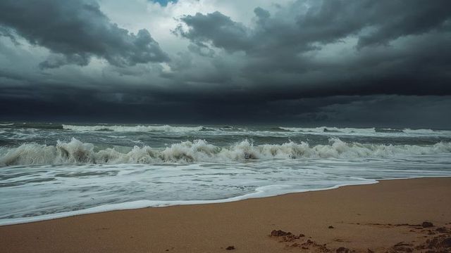 Dramatic ocean waves and storm clouds at sandy beach