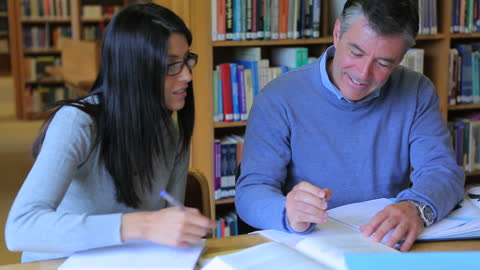 Two People Collaborating in a Library with Books and Notes