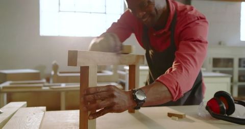 Skilled Craftsman Sanding Wooden Bench in Workshop