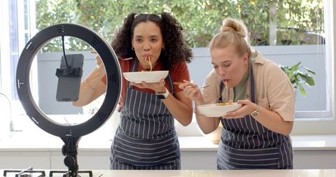 Female friends filming culinary content in modern kitchen