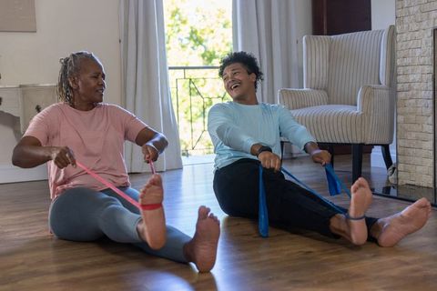 Senior african american couple working out at home with resistance bands, laughing together