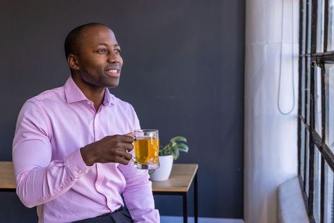 Businessman relaxing with beer in office lounge by window