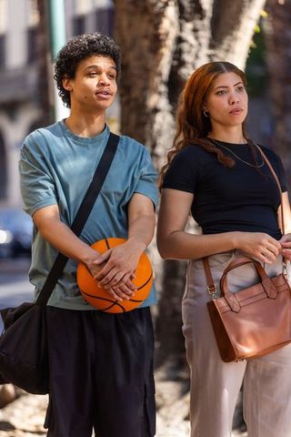 African american young couple standing on urban sidewalk holding basketball and handbag