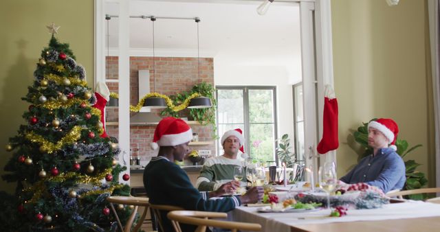 Friends sitting at a table in a festively decorated dining room, enjoying Christmas together. Christmas tree with ornaments and tinsel is present. Ideal for use in holiday greeting cards, festive promotions, social media, and lifestyle blogs sharing holiday cheer.