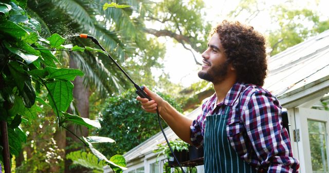 Guy Watering Plants in Backyard Garden on a Sunny Day - Download Free Stock Images Pikwizard.com