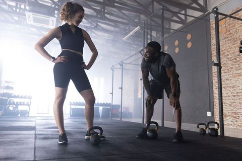 Female athlete training with african american coach using kettlebells in industrial gym