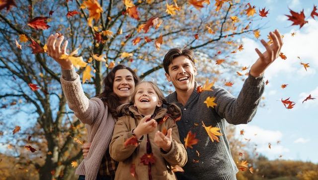 Happy family celebrating autumn with falling maple leaves
