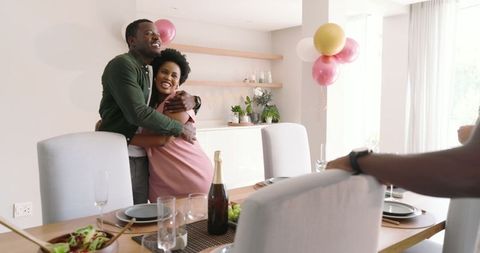 Joyful friends hugging during cozy home gathering celebration